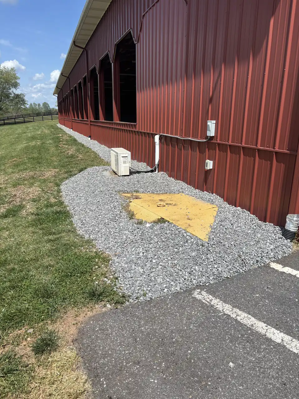 Gravel pad along the side of a red barn