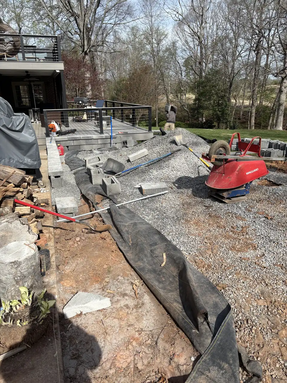 Crushed stone base spread over fabric, with a plate compactor on it