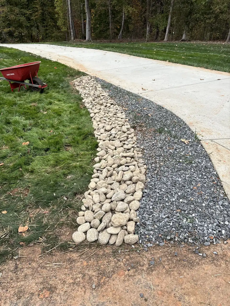 River rock dry creek bed running beside a concrete driveway