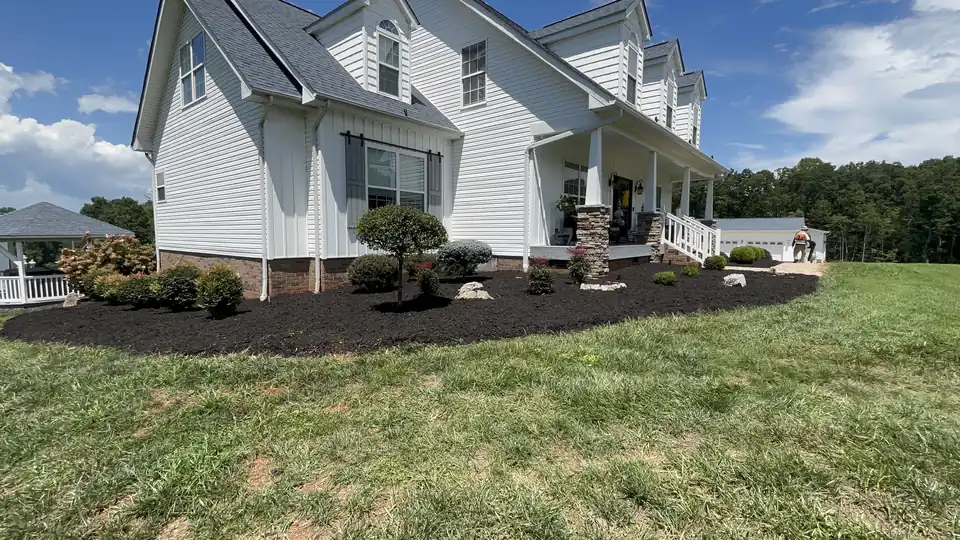 Fresh mulch beds across the front of a white house