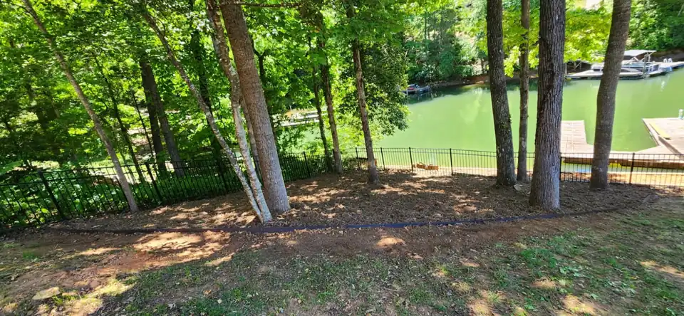 After: An overgrown lakefront slope cleared back to the fence, raked out and edged, opening up the view of the water