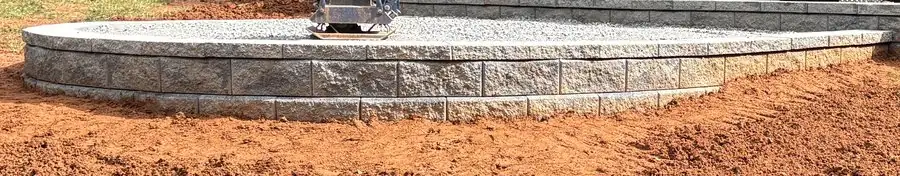 Red clay backfilled and packed against the base of a new block wall