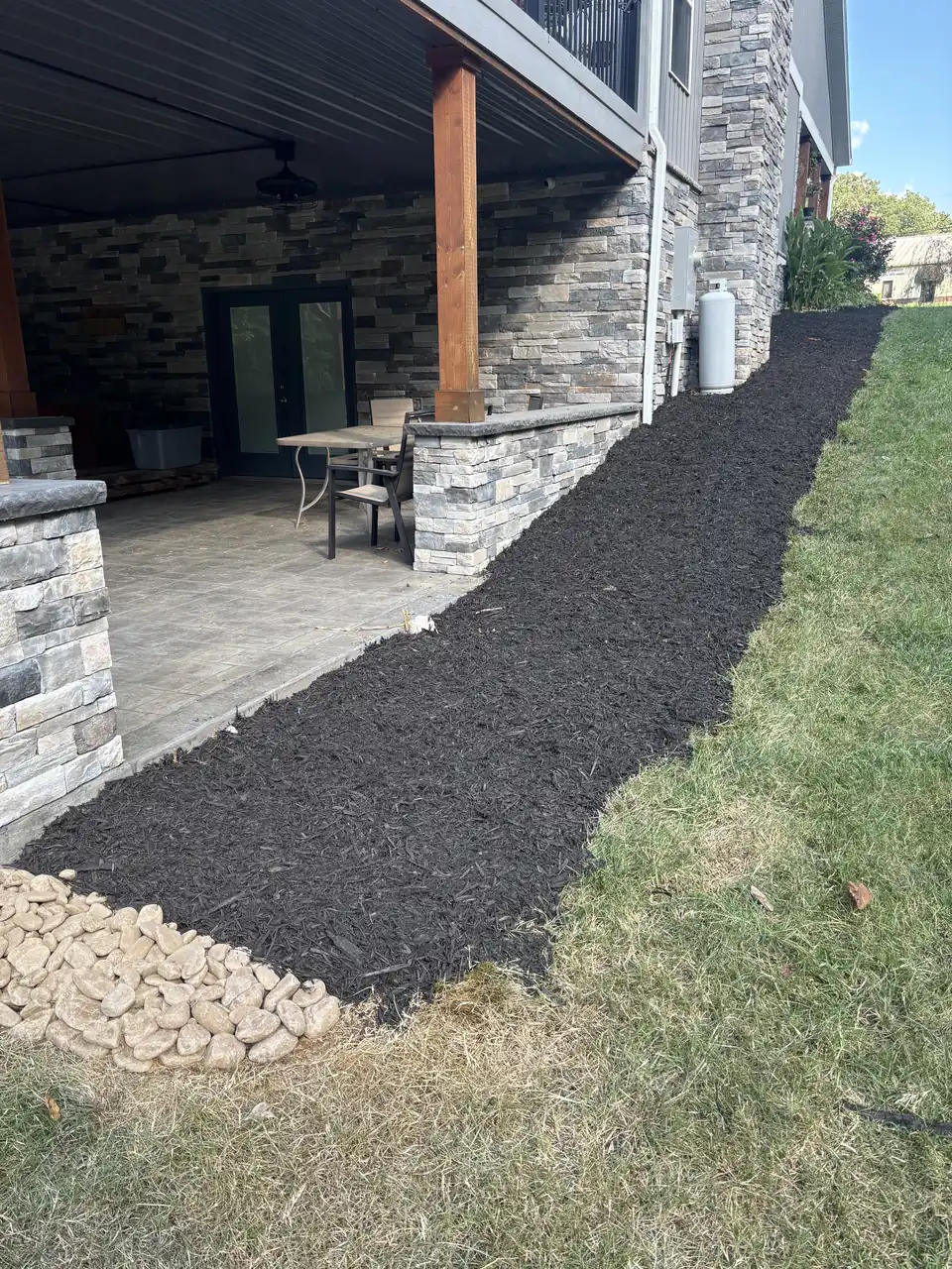 Mulch line and river rock along a covered patio