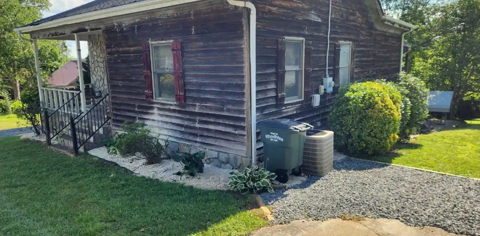 After: Overgrown shrubs along a cottage replaced with a rock bed and gravel