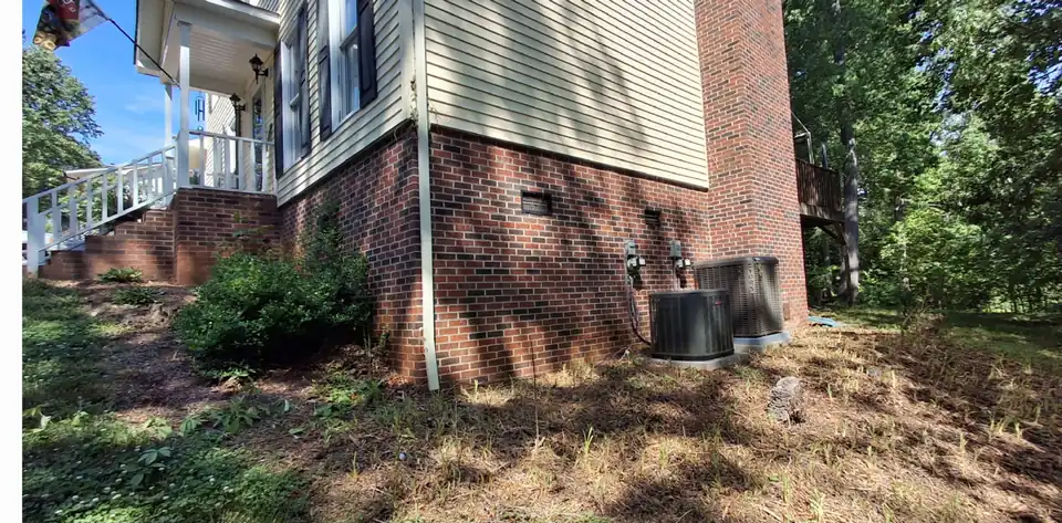 Before: Bare ground along a brick foundation turned into a stone-edged rock bed
